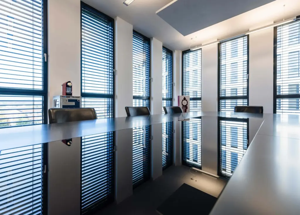 Moderner Besprechungsraum mit maßgefertigtem Konferenztisch und großen Fensterfronten von Schreinerei Engelmann