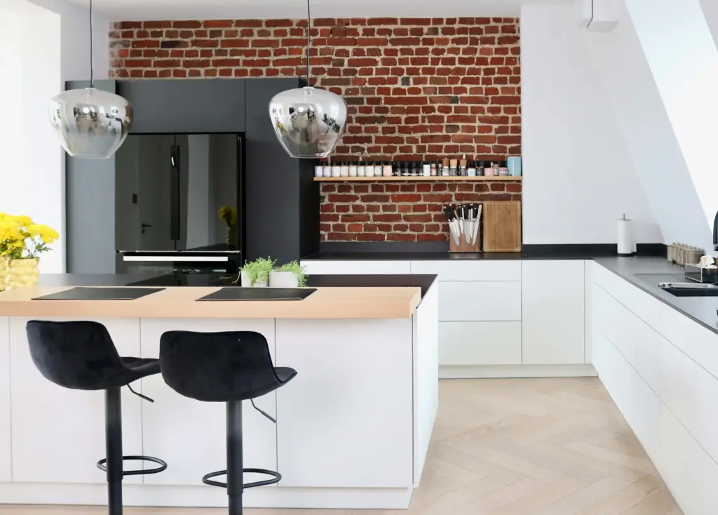 Moderne maßgefertigte Küche mit Kochinsel, heller Front und Backsteinwand von Schreinerei Engelmann