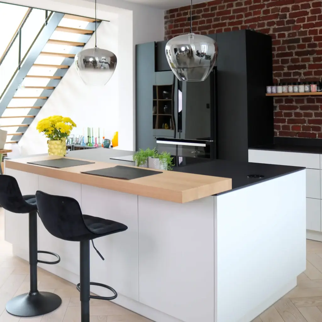 Moderne maßgefertigte Küche mit Kochinsel, Holzarbeitsplatte und dunklen Akzenten von Schreinerei Engelmann