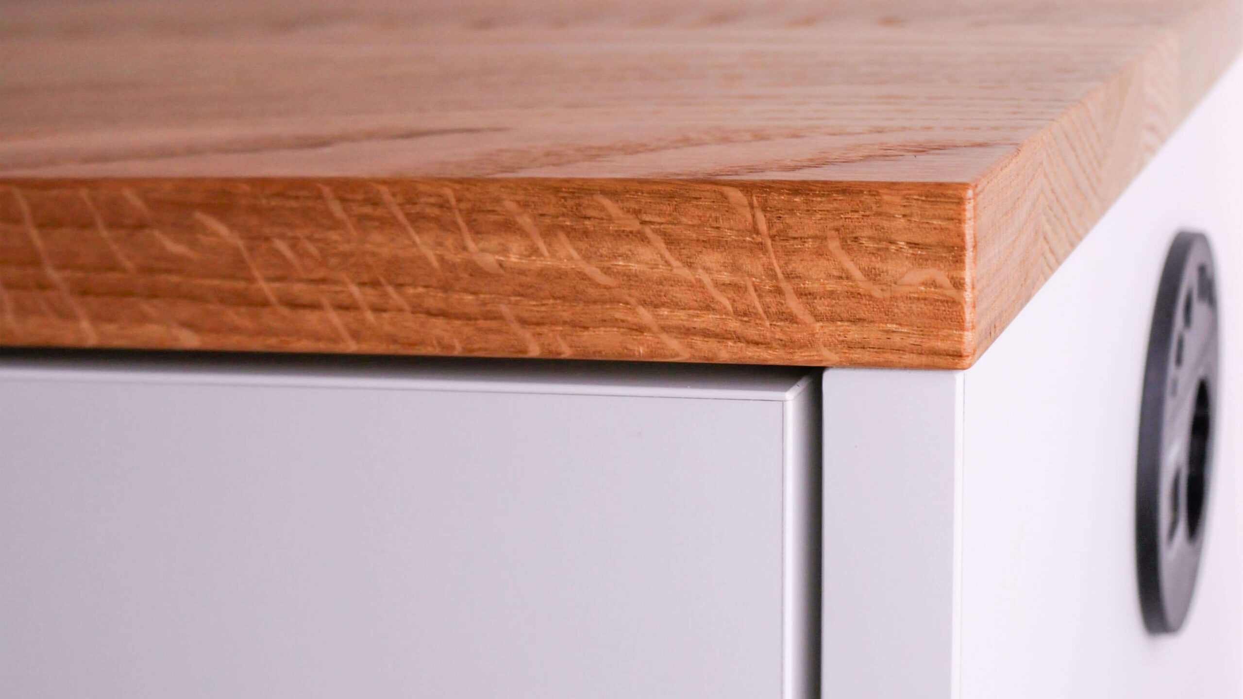 Detailaufnahme der Eiche-Abdeckung und weißen Front eines maßgefertigten Sideboards