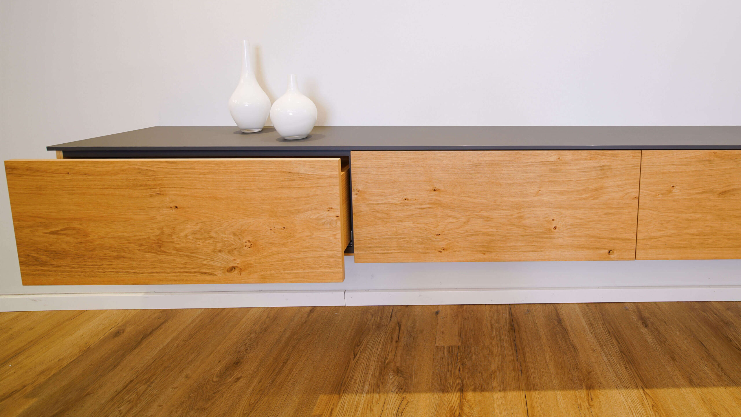 Hängendes Sideboard aus Eiche mit geöffneter Schublade und anthrazitfarbener Abdeckplatte