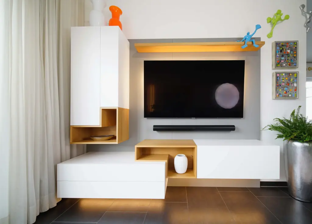 Maßgefertigte Wohnwand mit TV-Möbel, offenen Holzfächern und weißer Front von Schreinerei Engelmann