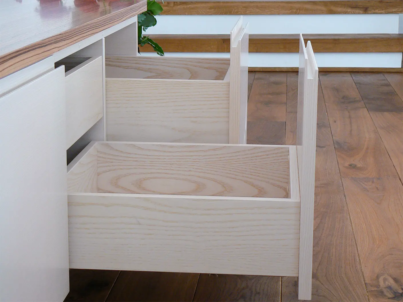 Geöffneter Auszug eines maßgefertigten weißen Sideboards mit Stauraum aus hellem Holz